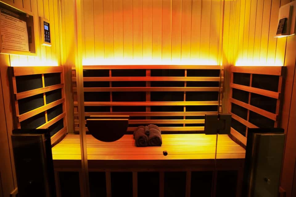Infrared sauna interior with wooden benches, warm ambient lighting, and towel placement