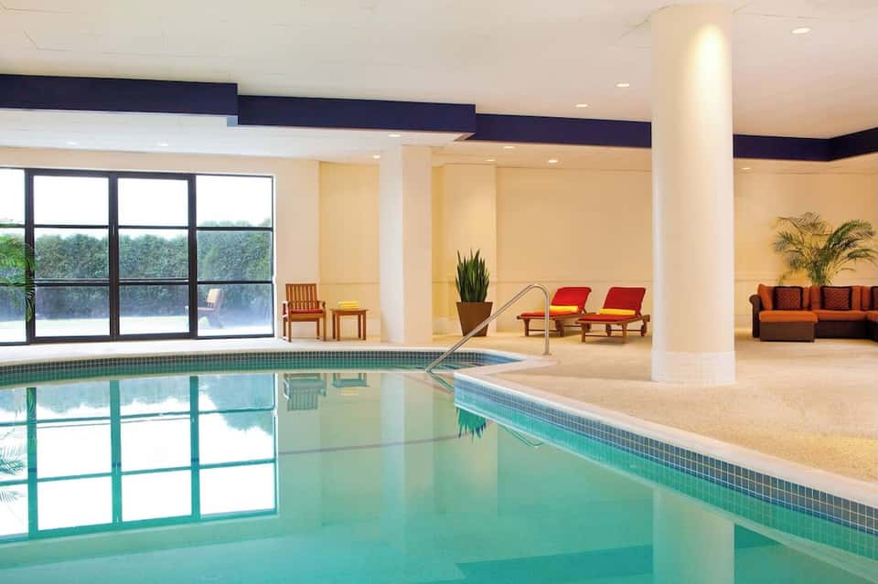 Indoor swimming pool with large windows, lounge seating area, and modern architecture