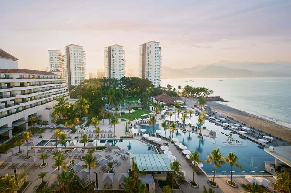Beachfront resort aerial view with multiple pools, palm trees, and ocean