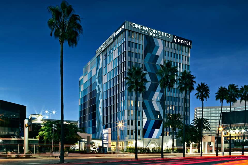 Homewood Suites hotel building at night with palm trees and blue signage