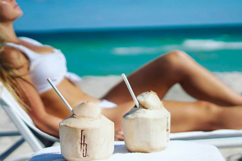 Woman relaxing on beach chair with coconut drinks and turquoise ocean view