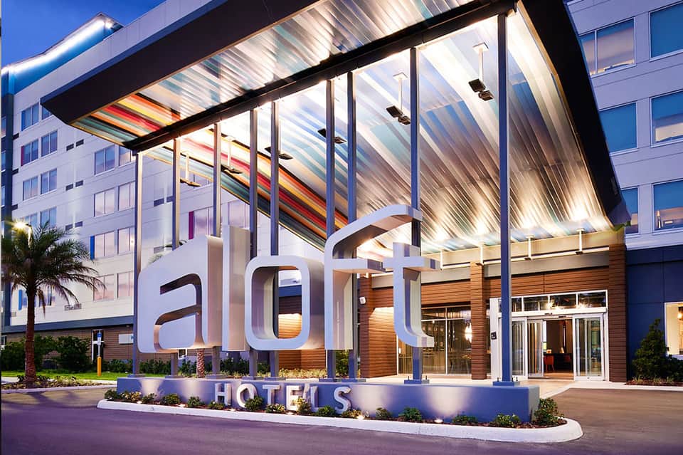 Modern hotel entrance with illuminated aloft sign and contemporary architecture at dusk