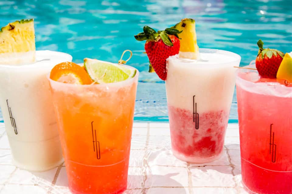 Colorful tropical cocktails by poolside with fruit garnishes and ice
