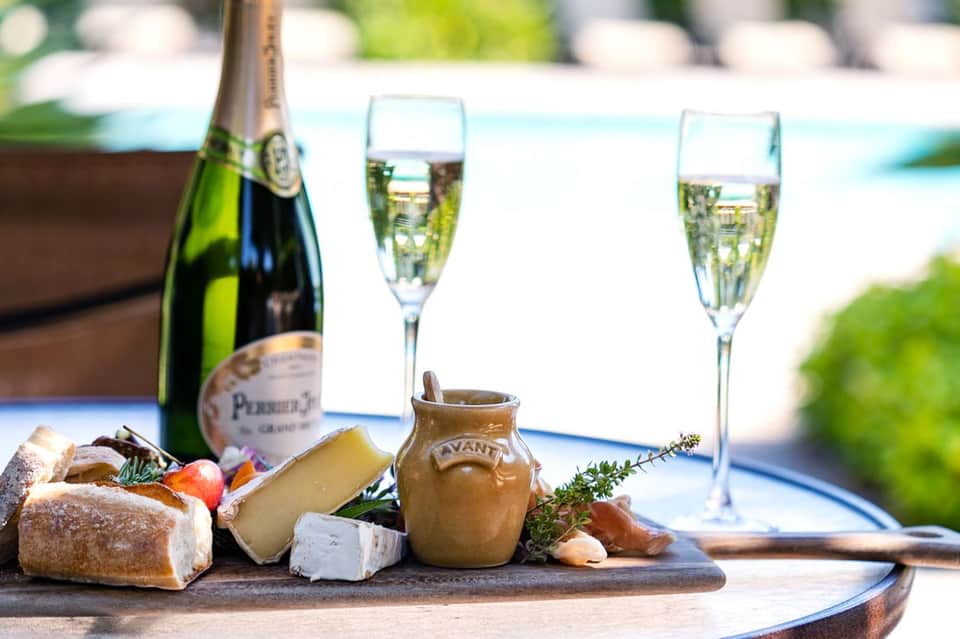 Champagne bottle and flutes with gourmet charcuterie board overlooking a resort pool