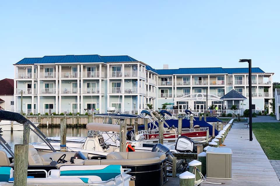 Waterfront resort with white multi-story buildings, blue roofs, and docked boats at marina