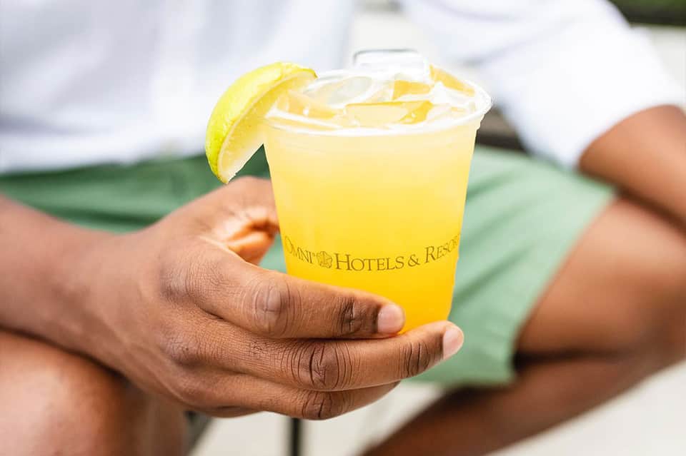 Guest holding a yellow lemonade with lime slice at an omni hotels and resorts property