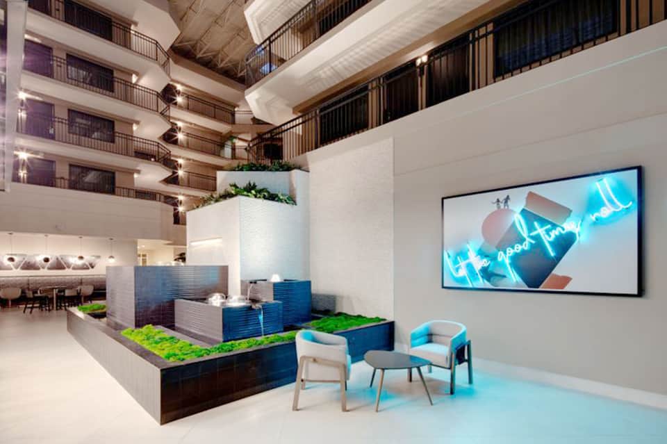 Modern hotel lobby with multi-level balconies, living wall, and contemporary seating area