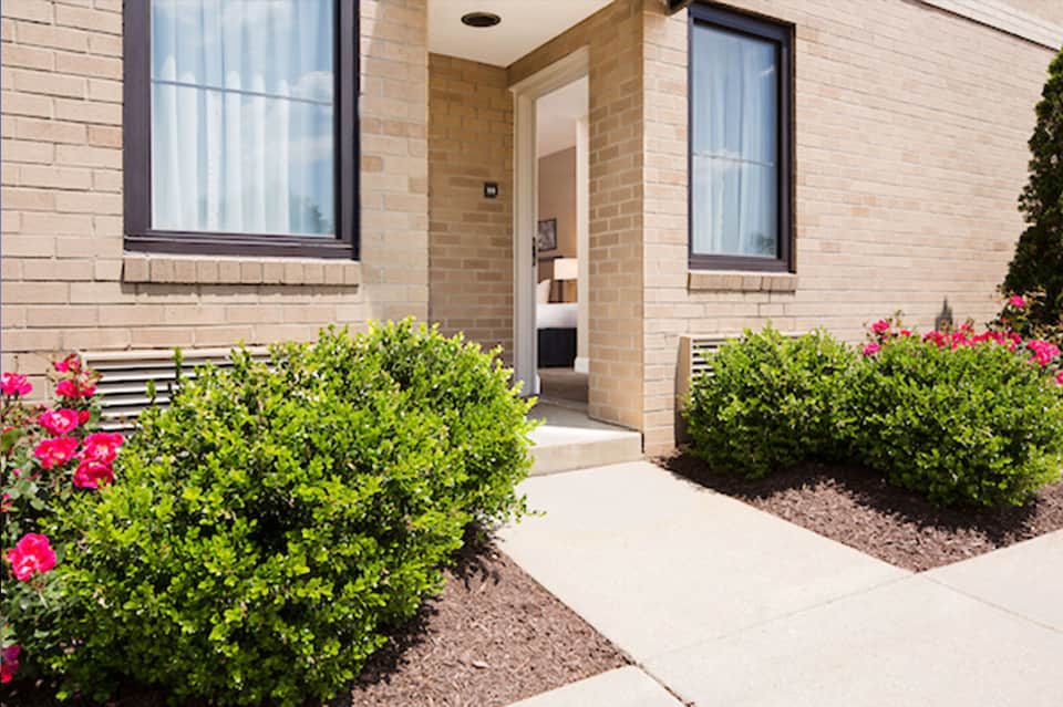 Brick residential entrance with manicured landscaping and pink flowering shrubs