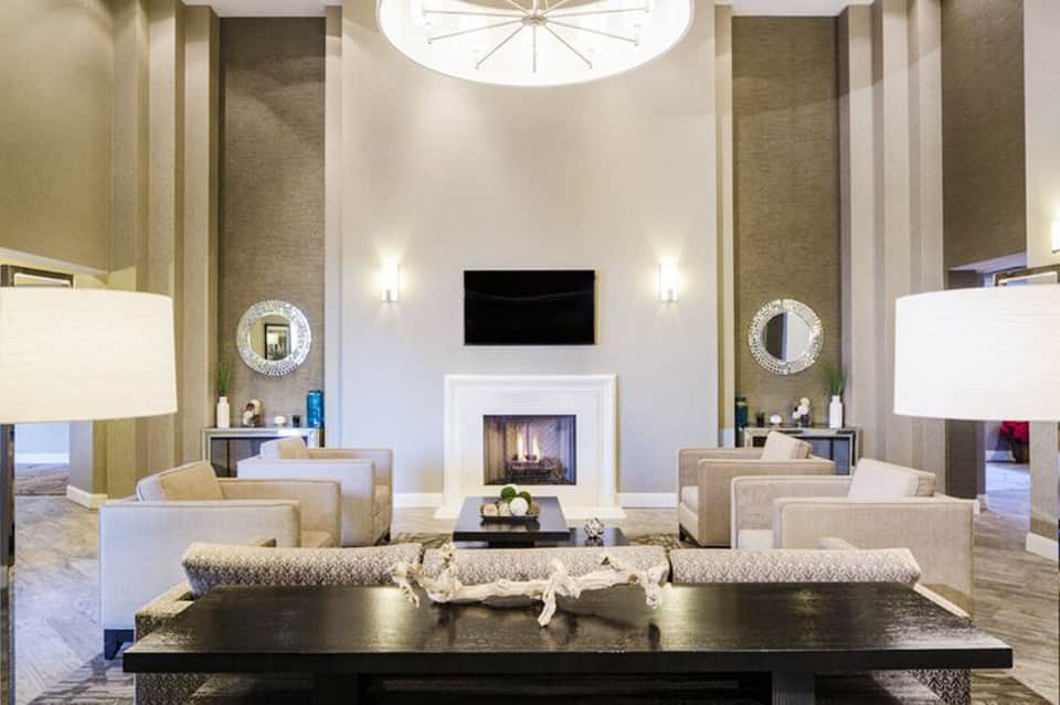 Modern luxury hotel lobby with fireplace, elegant seating, mirrored accents, and contemporary lighting