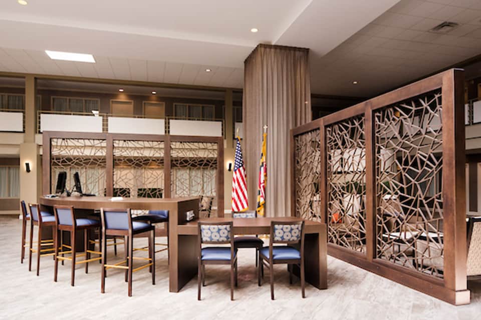 Modern hotel lobby with wooden decorative panels, bar seating, and contemporary furnishings