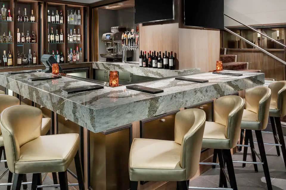 Upscale bar lounge with marble counter, cream leather seating, wine display, and modern decor