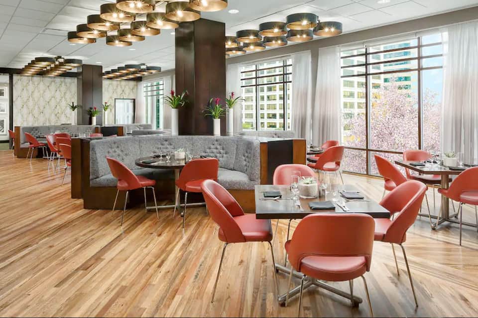 Modern upscale restaurant with gold pendant lights, red chairs, wood flooring, and city views