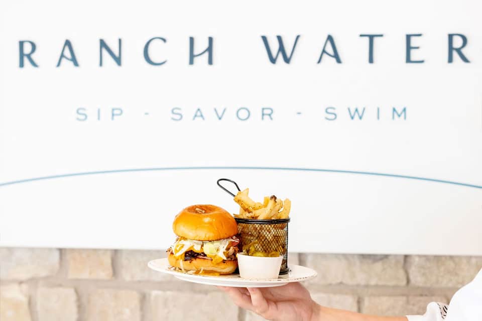 Ranch Water restaurant branding with server holding plate of burger, fries, and drink