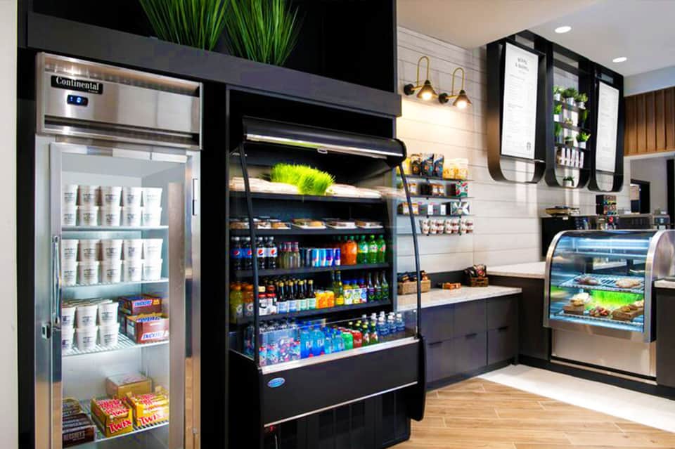 Modern convenience store with refrigerated beverages, black display cases, snack shelves, and gold accent lighting
