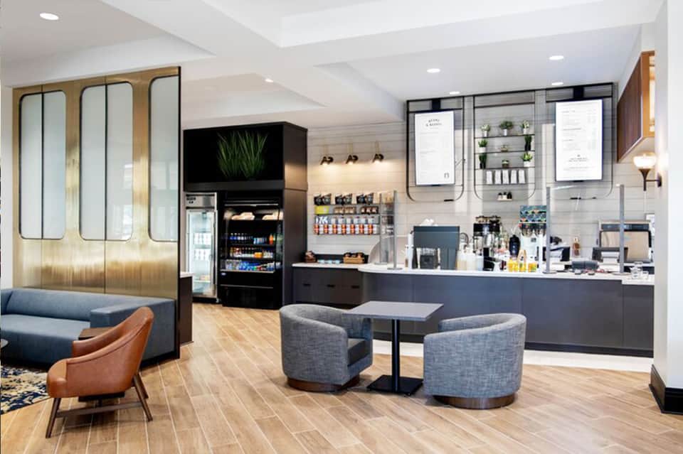 Modern hotel lobby with black and gold accents, seating areas, and coffee bar