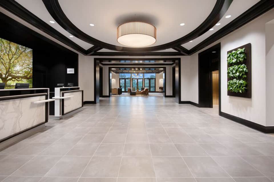 Modern hotel lobby with black and white marble floors, curved ceiling, and green plant wall