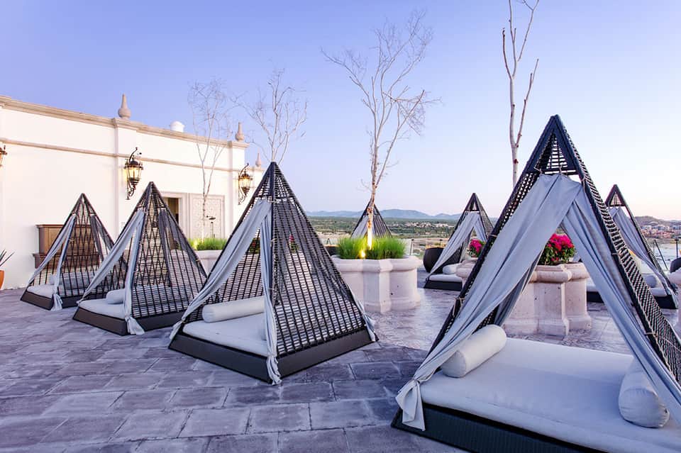 Outdoor terrace with pyramid-shaped loungers and white drapes overlooking valley landscape