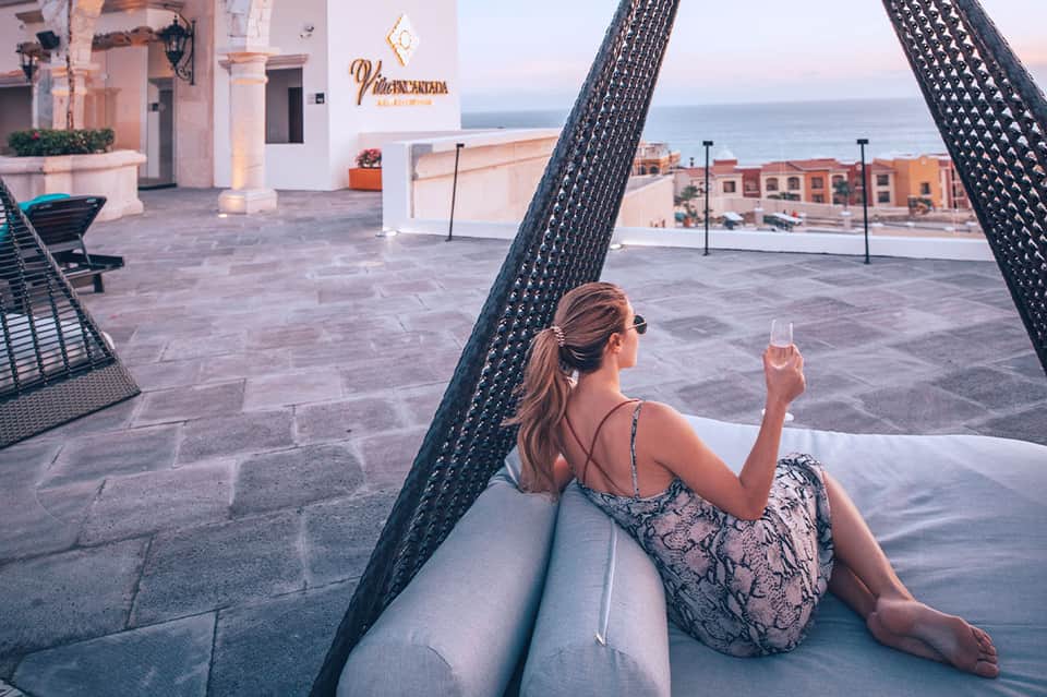 Woman relaxing in hammock with wine glass overlooking coastal Mediterranean resort