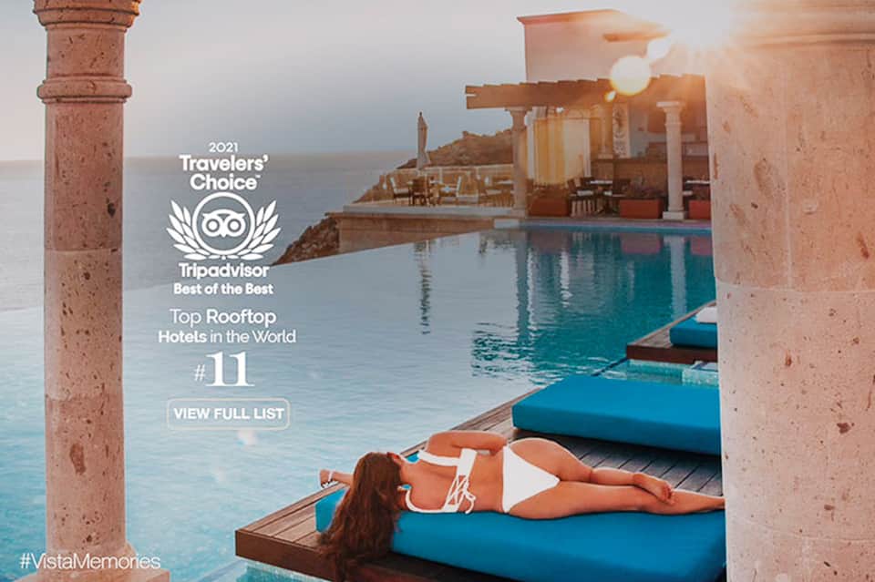 Woman sunbathing on blue lounger by infinity pool overlooking sea at luxury rooftop hotel