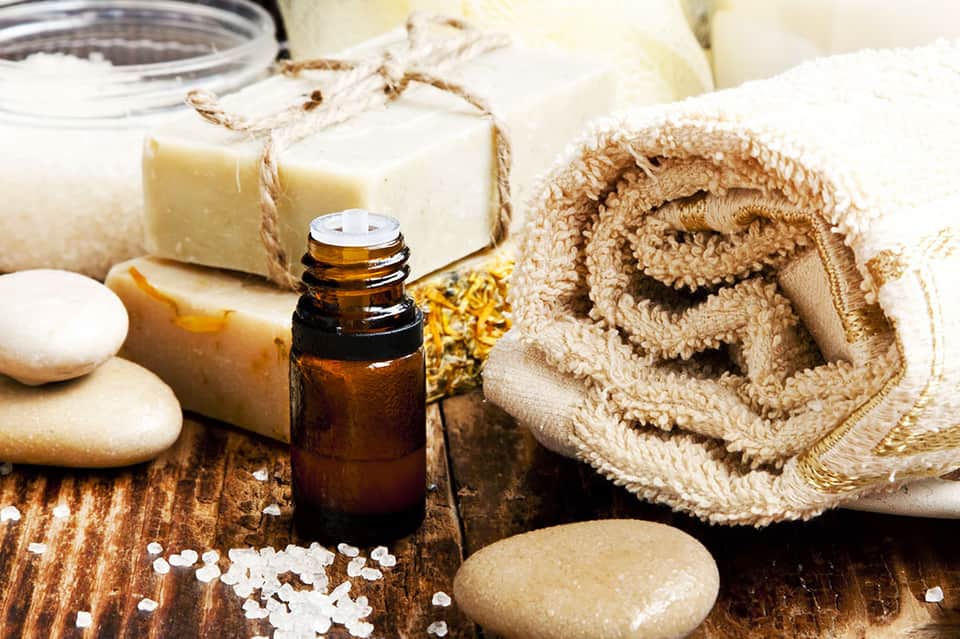 Spa essentials including essential oil, soap, sea salt, towels, and stones
