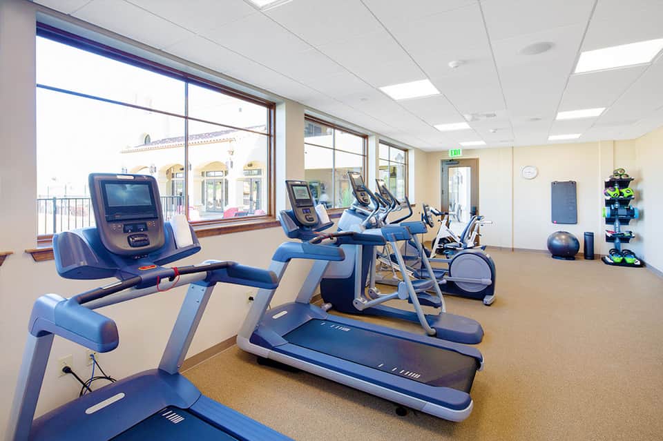 Modern fitness center with treadmills, stationary bikes, and exercise equipment with ocean views