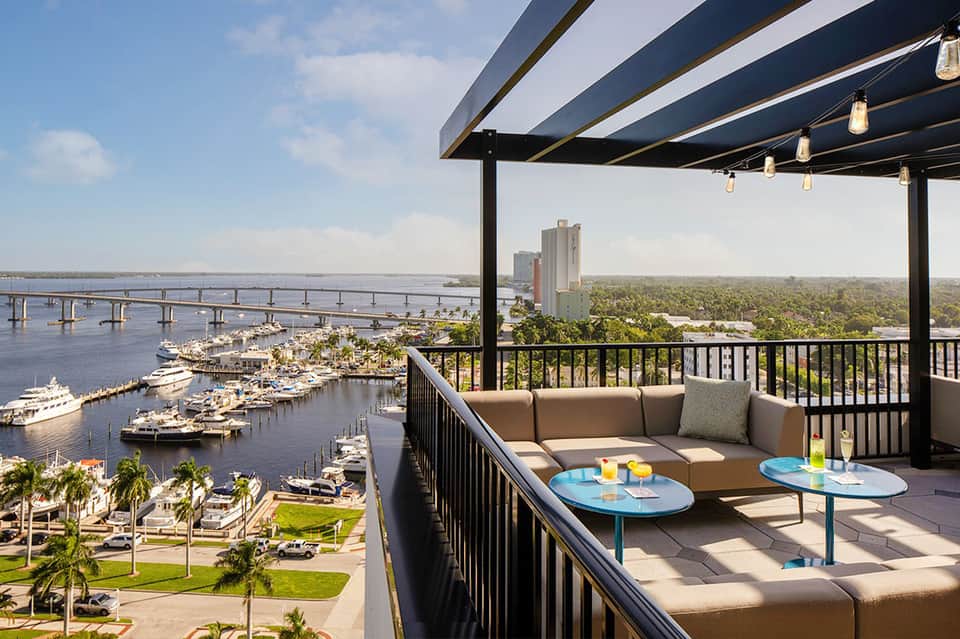 Elevated lounge area overlooking marina with boats, bridge, and waterfront cityscape views