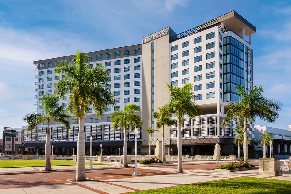 Luminary Hotel exterior with modern architecture, palm trees, and ground-level retail space