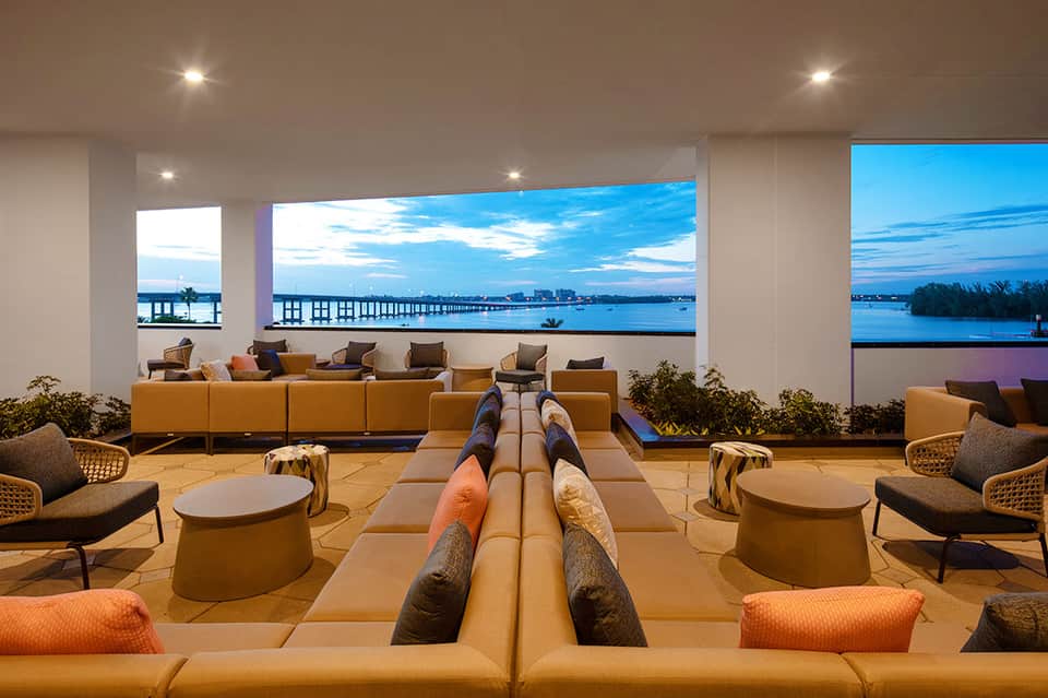 Elegant lounge with orange seating, geometric design, and waterfront views through large windows