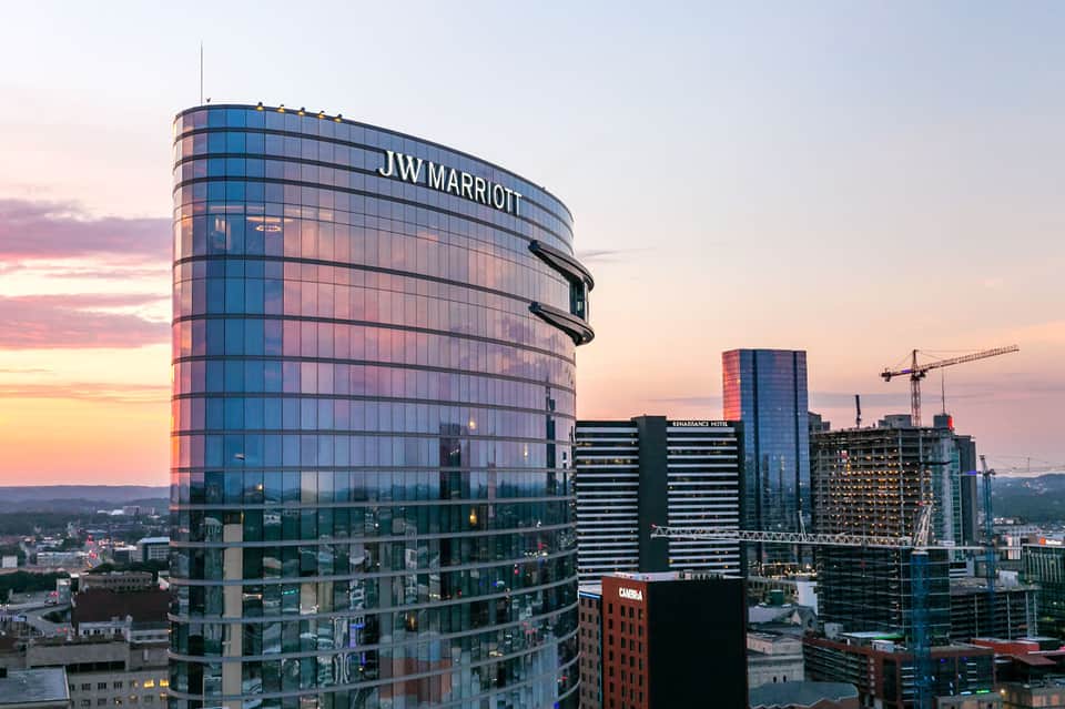 JW Marriott cylindrical hotel tower illuminated at dusk in a modern cityscape