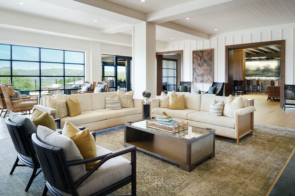 Luxury living room with cream sectional sofas, yellow accent pillows, and expansive windows overlooking countryside landscape