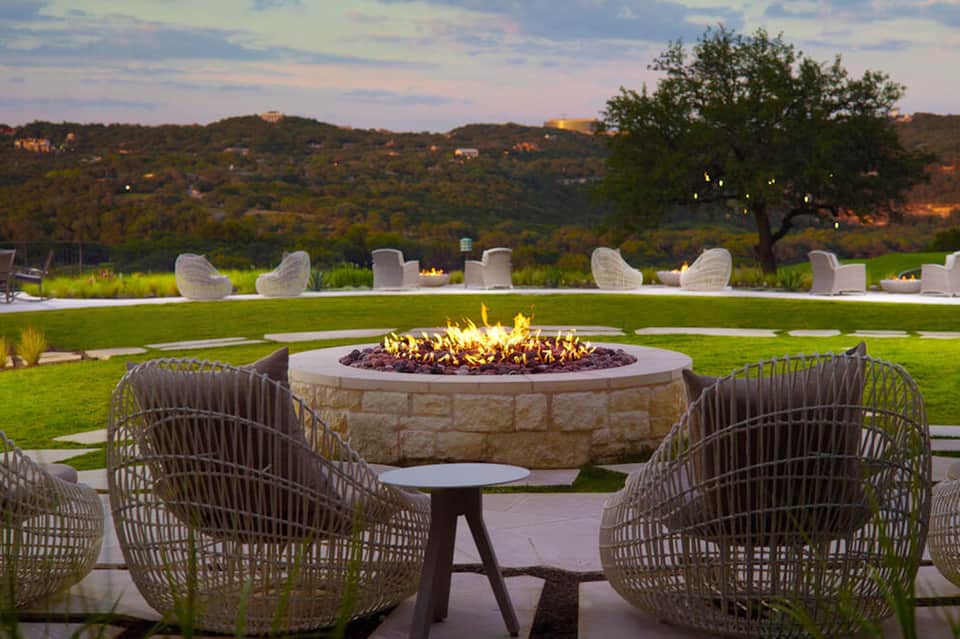 Outdoor fire pit seating area with modern chairs overlooking rolling hills and landscape