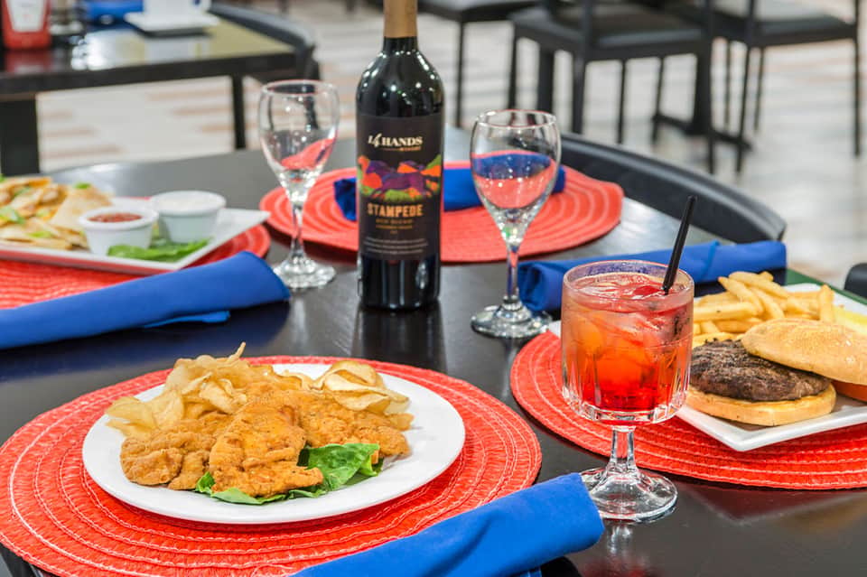 Dining table set with seafood dishes, wine glasses, red and blue placemats, and wine bottle