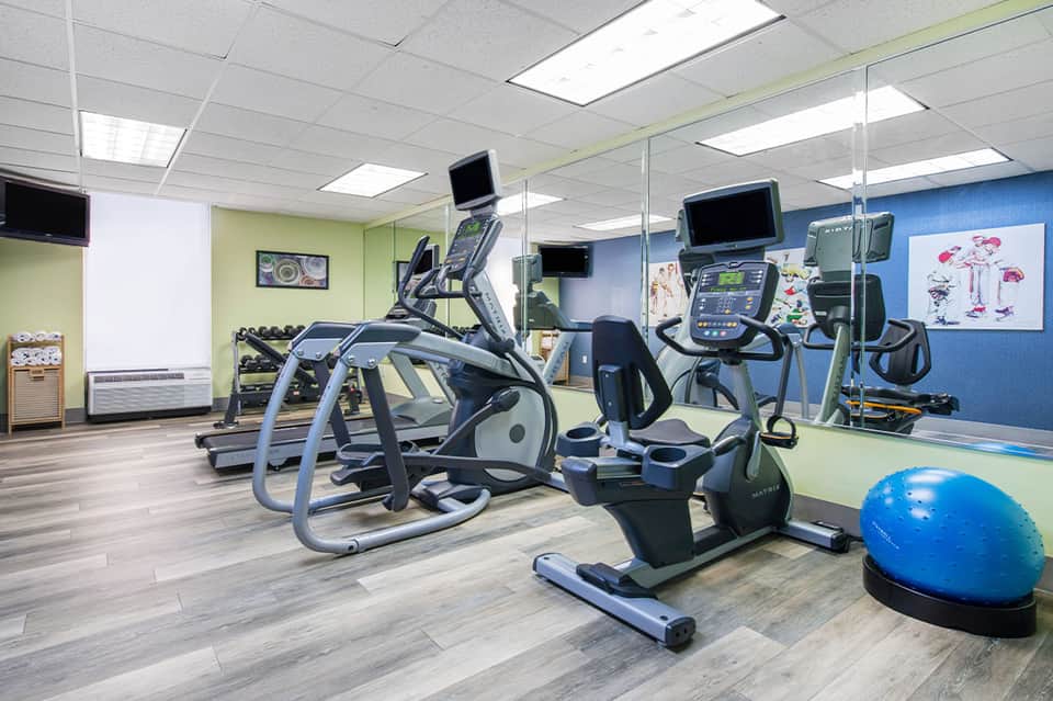 Modern fitness center with elliptical machines, exercise bikes, blue stability ball, and colorful wall accents