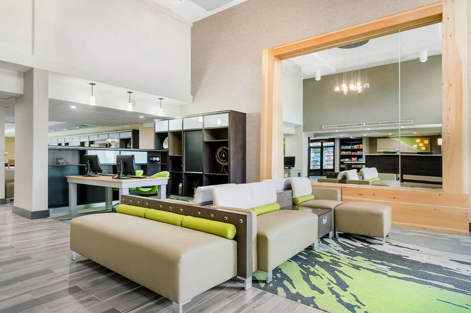 Modern hotel lobby with cream seating, lime green accents, and contemporary architectural design