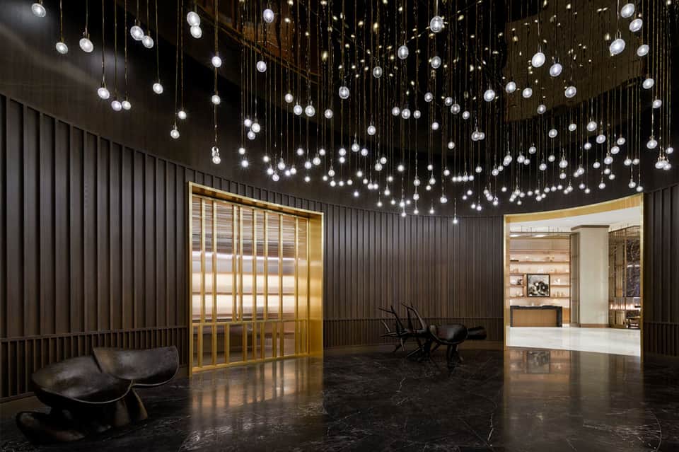 Contemporary hotel lobby with hanging crystal pendant lights and gold-framed doors