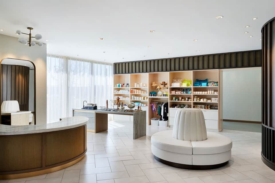 Modern spa reception area with curved white desk, shelving displays, and minimalist interior design