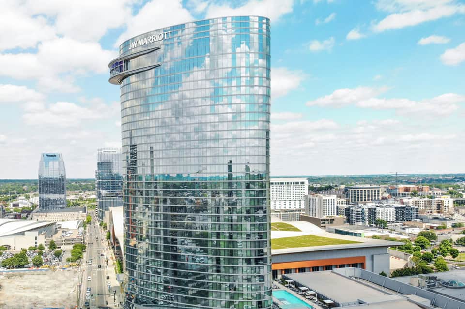 Circular tower hotel with JW Marriott signage overlooking cityscape and rooftop pool