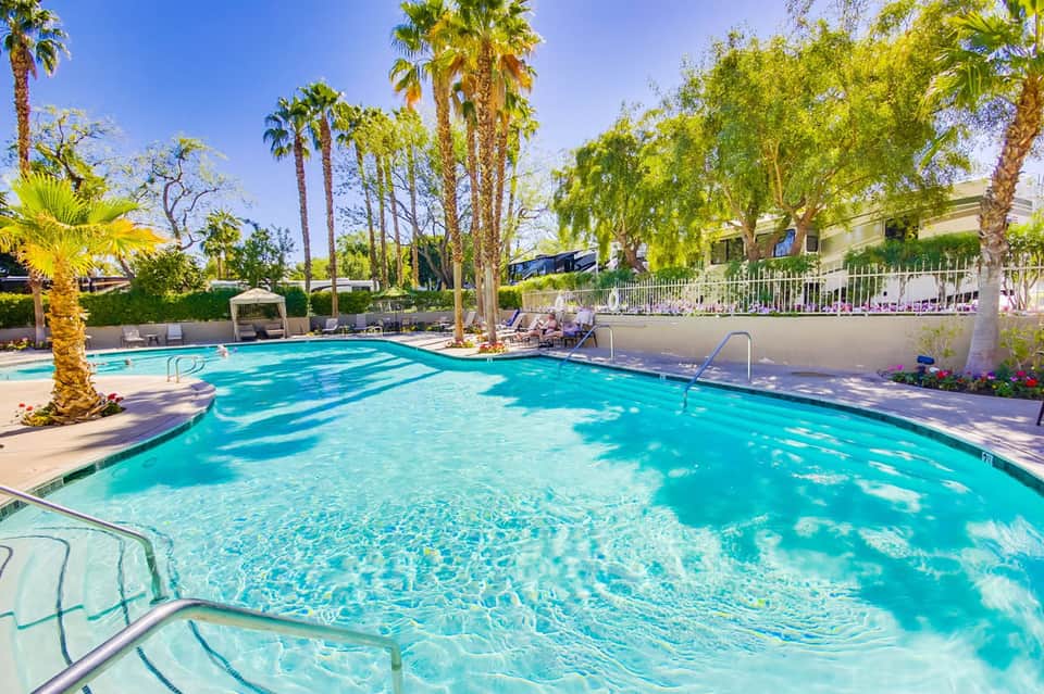 Resort swimming pool with crystal-clear turquoise water, palm trees, and lounge chairs