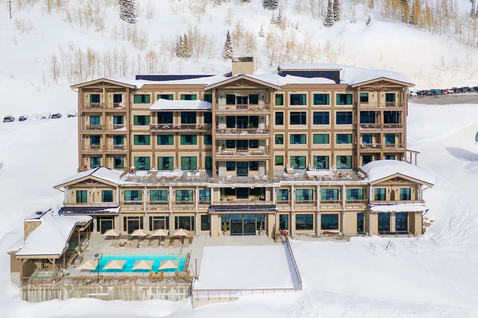 Aerial view of large luxury resort hotel surrounded by snowy landscape with frozen lake nearby