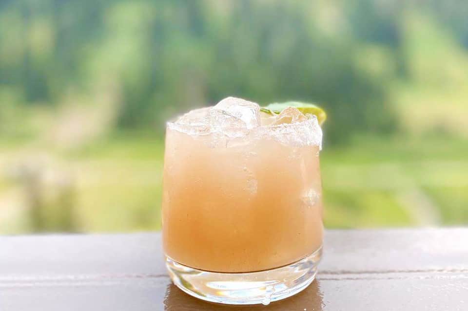 Refreshing citrus cocktail with ice and lime garnish on blurred tropical background