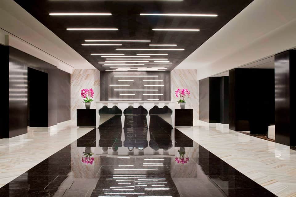 Minimalist hotel lobby with black and white marble floors and pink floral arrangements