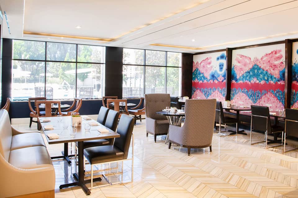 Modern fine dining restaurant with floor-to-ceiling windows, contemporary art, and wood accents