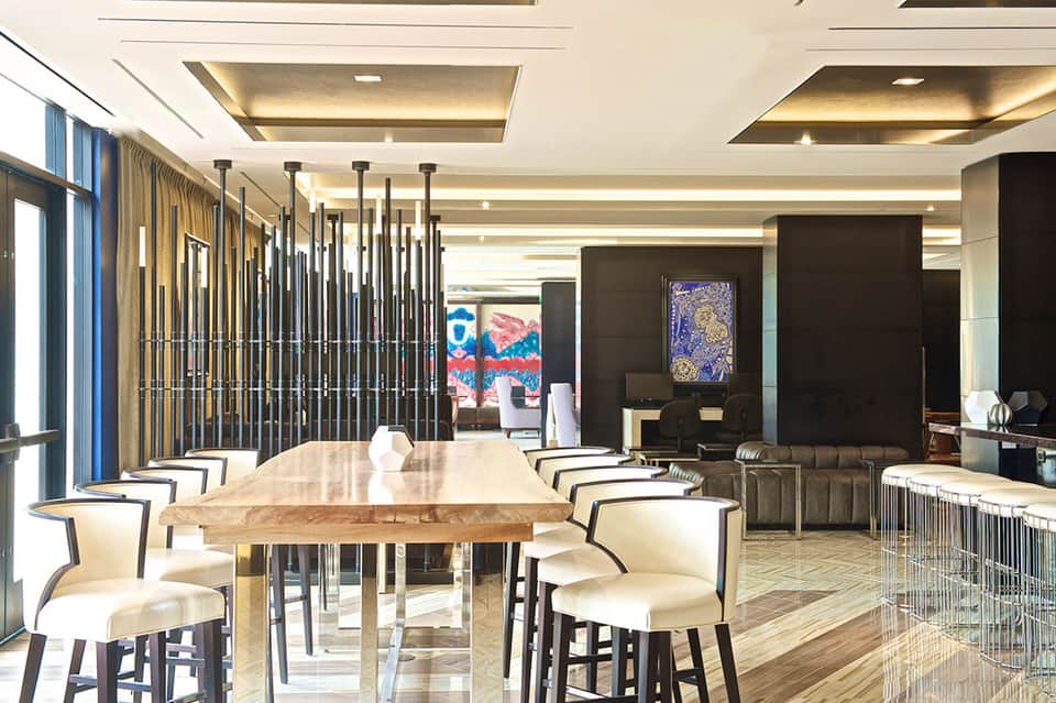 Modern dining area with wooden table, white chairs, and geometric wall art