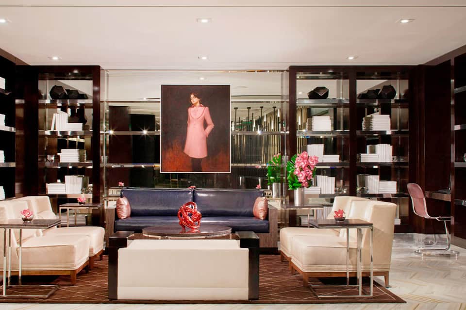 Luxury hotel lobby with dark wood shelving, cream seating, and modern art accents