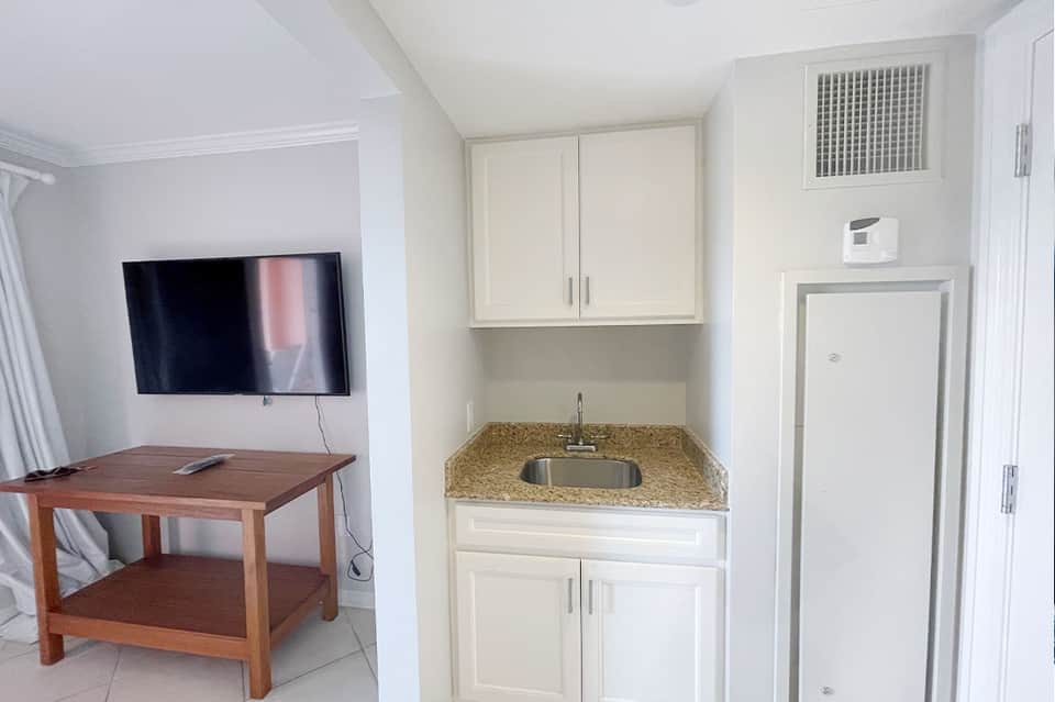 Hotel room kitchenette with granite countertop, sink, and television