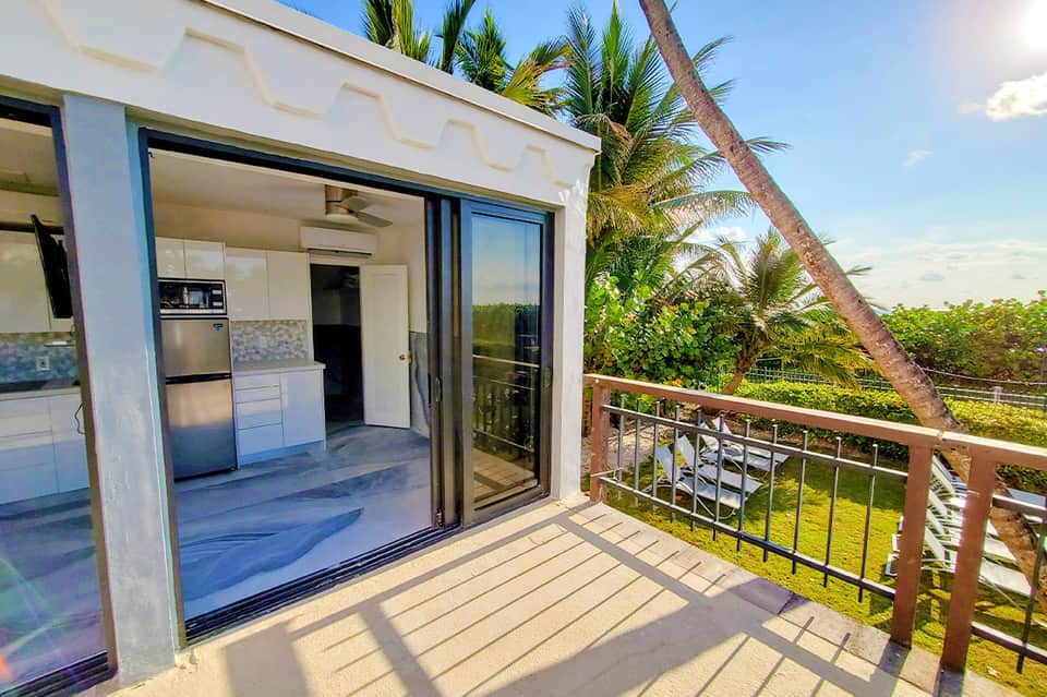Modern beachfront condo unit with white kitchen, open-concept living, and ocean view balcony