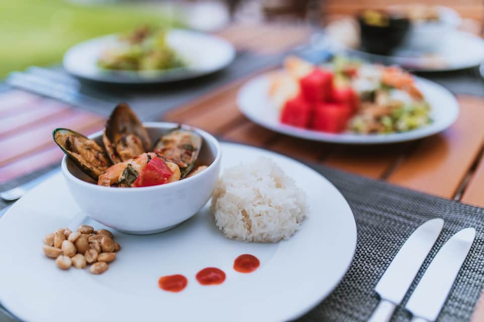 Fine dining plate with seafood, rice, and garnish on outdoor table