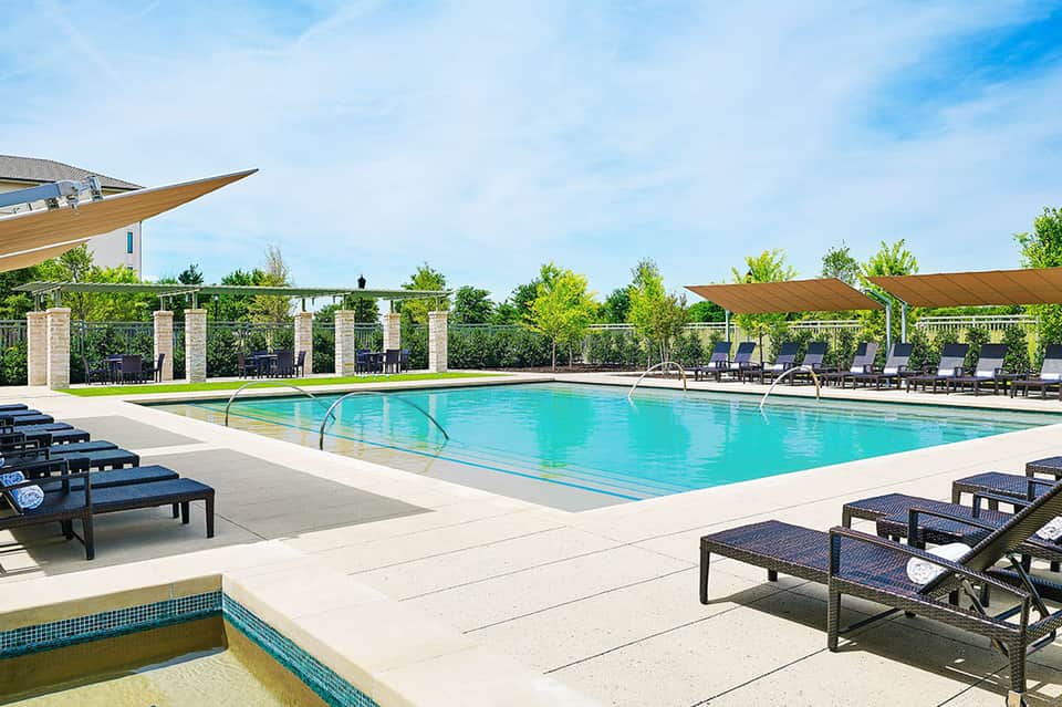 Olympic-size swimming pool with sun loungers, wooden pergola structures, and manicured landscaping