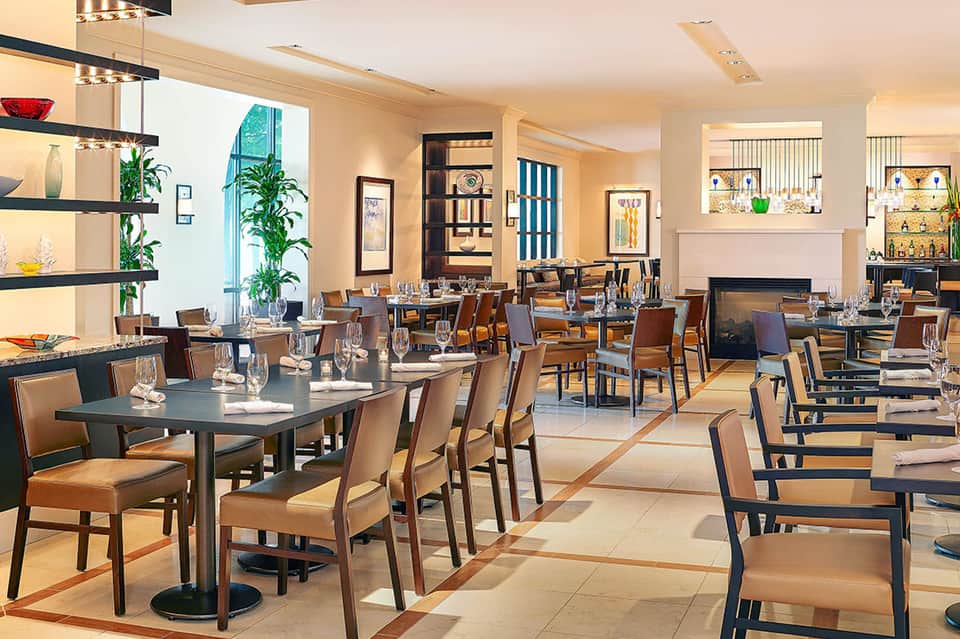 Elegant dining room with modern furnishings, plants, and contemporary décor overlooking multiple seating areas