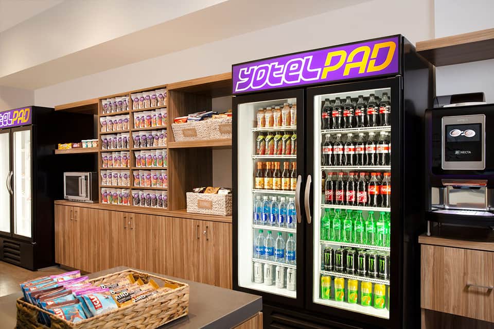 Modern snack bar interior with YodelPad branding, beverage coolers, and packaged snacks on wooden shelving